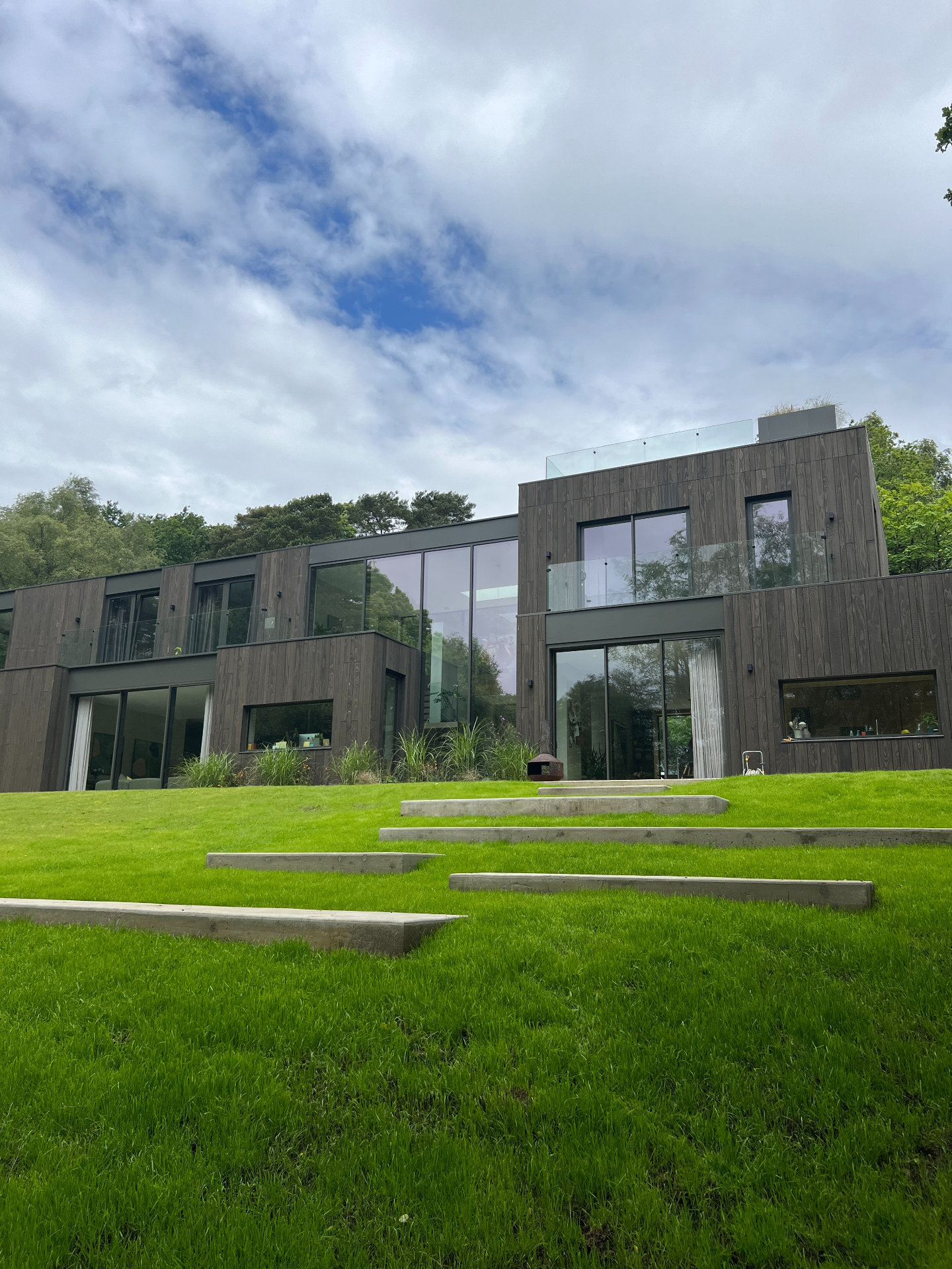 Cantilevered concrete steps rising through a sloping lawn