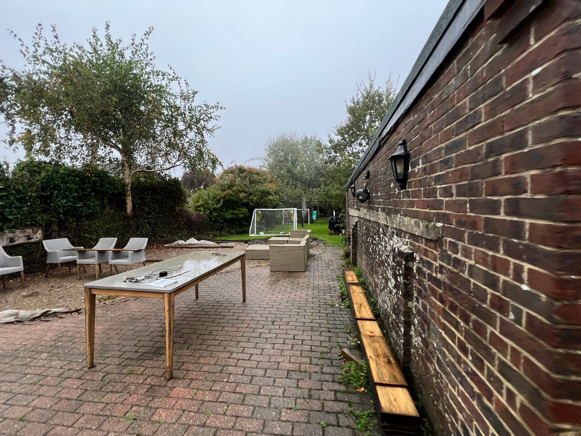 Original garden - dated block paving patio with rattan furniture and bare brick boundary