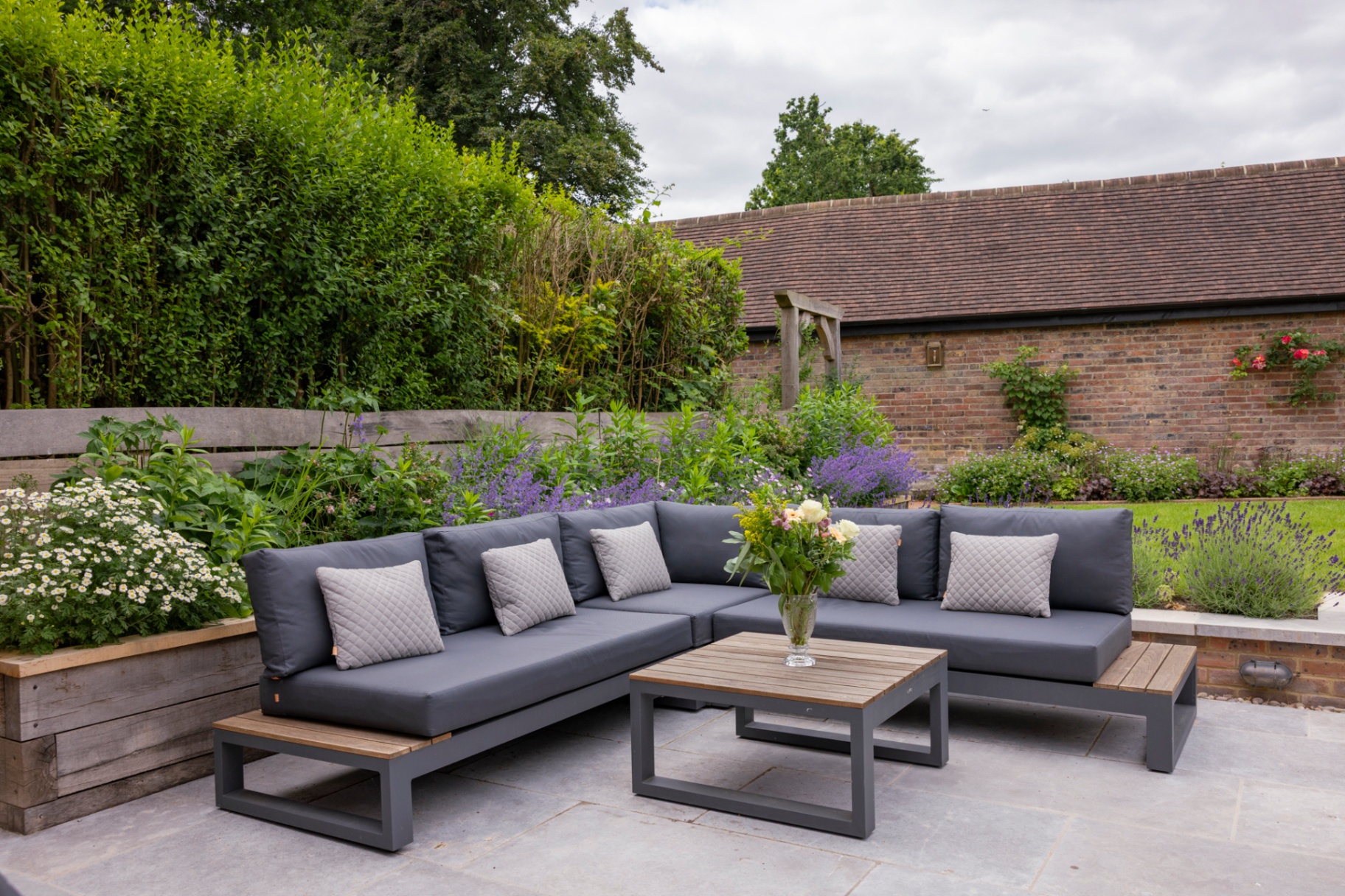 Outdoor lounge with cushioned sofa surrounded by cottage planting