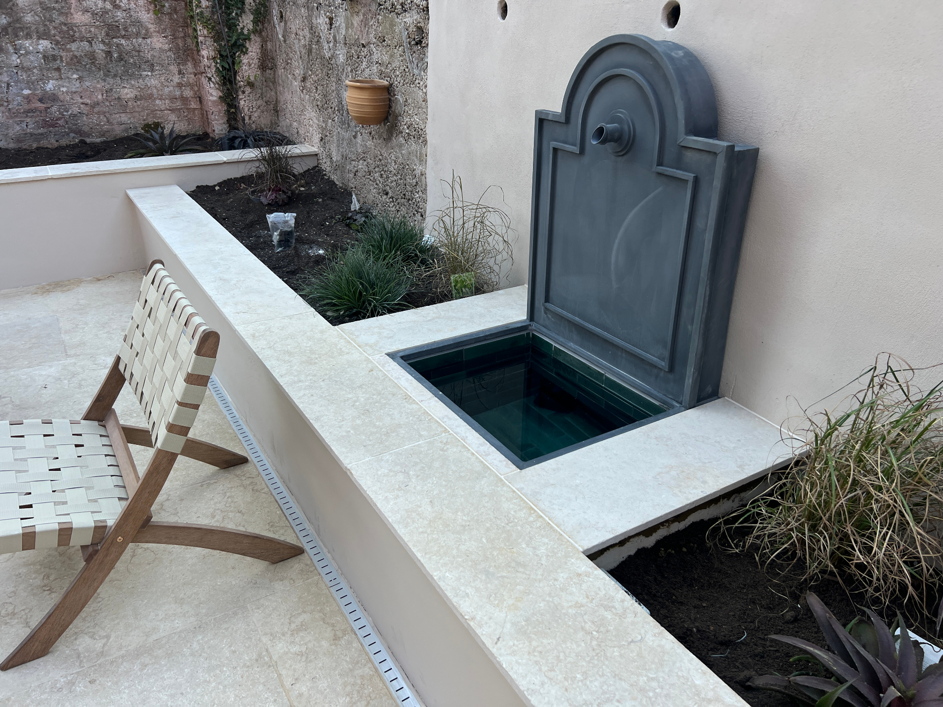 Medi Garden - lead wall fountain with green-tiled basin set into a travertine-capped raised bed