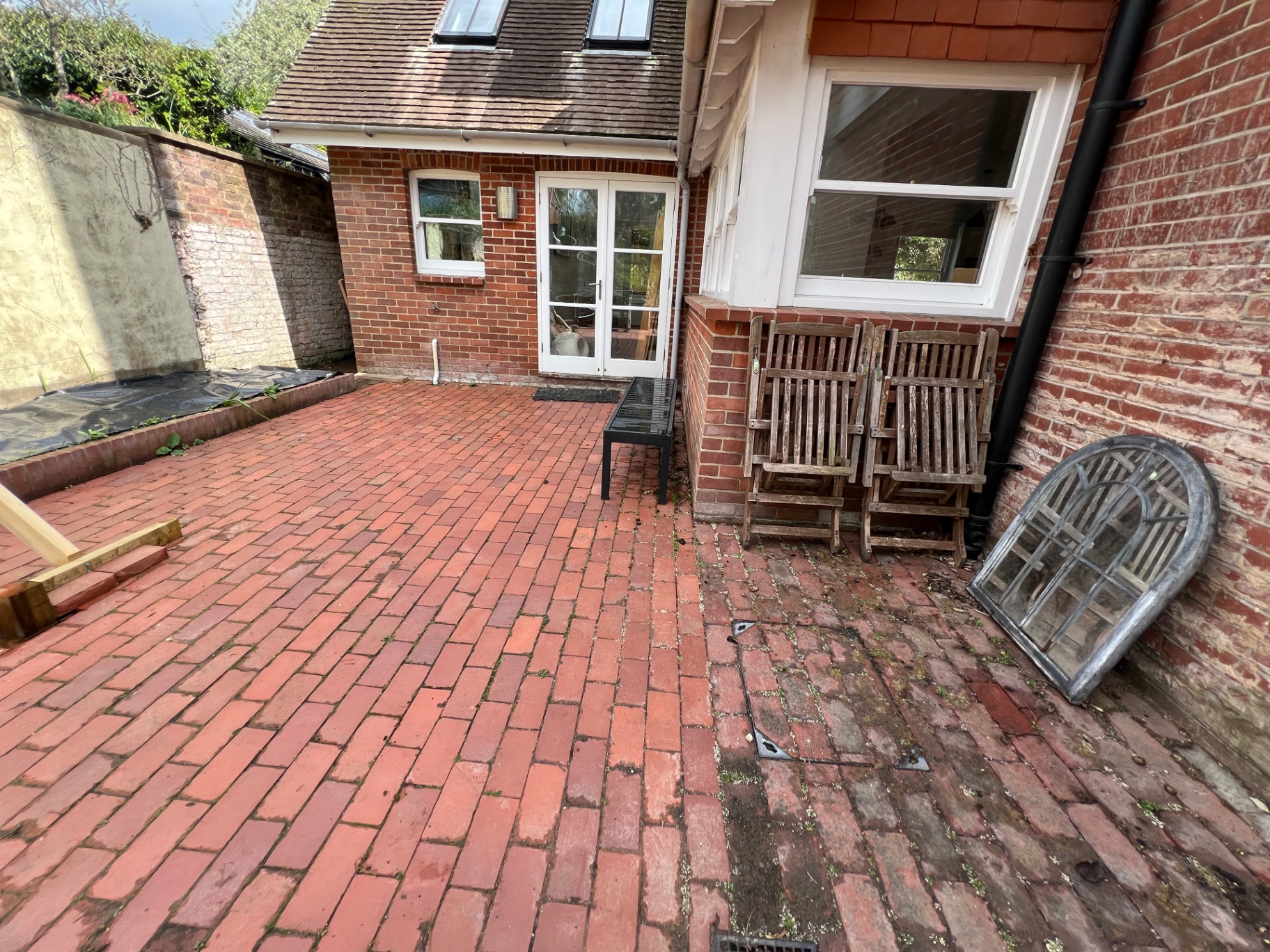 Original courtyard - tired red brick paving with mismatched timber chairs against the house