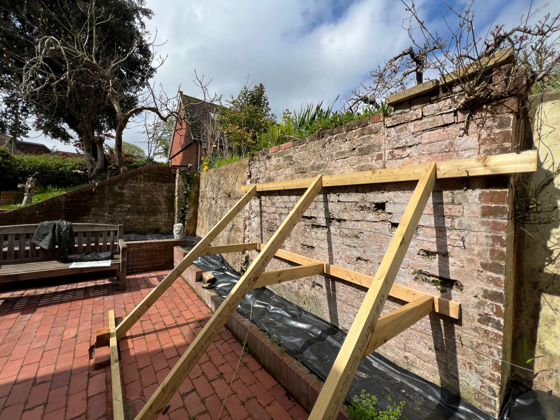 Original courtyard - crumbling brick wall with temporary timber bracing before restoration