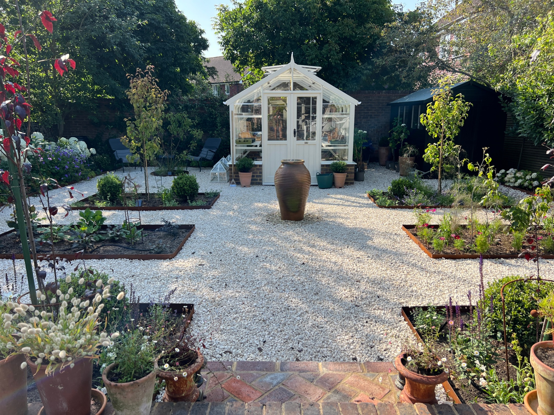 Finished gravel garden with bespoke greenhouse, raised beds and ornamental urn