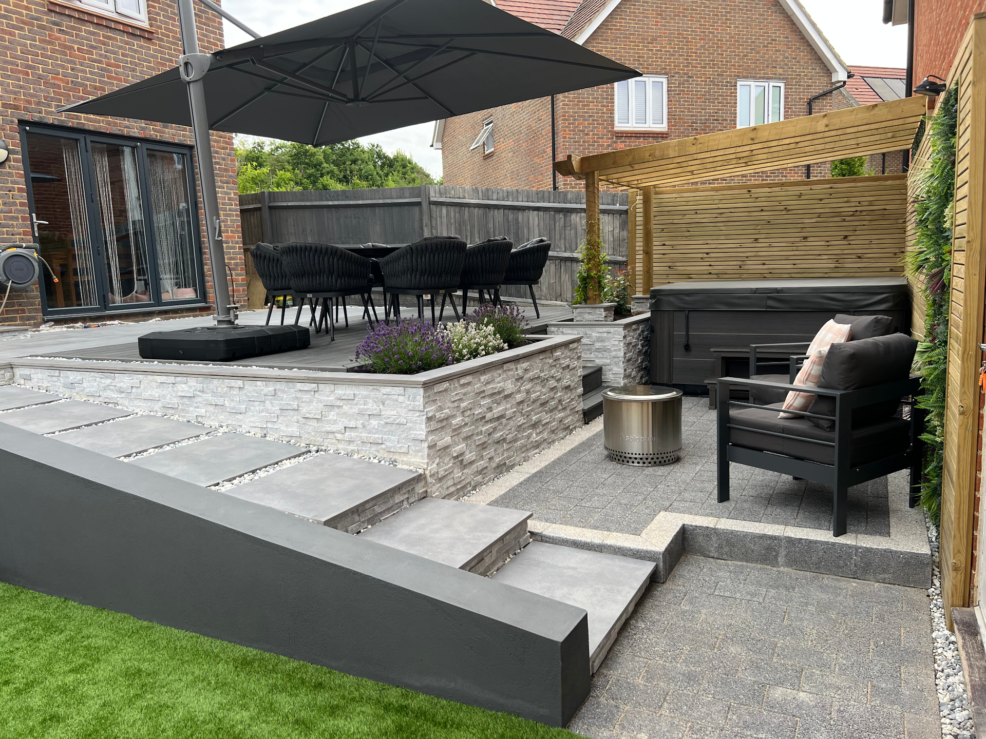 Finished garden - elevated dining terrace, pergola framing and layered stone-clad planters