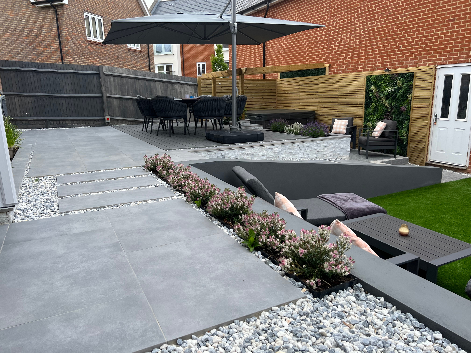 Finished garden - porcelain walkway leading to a sunken lounge, dining deck and richly planted borders