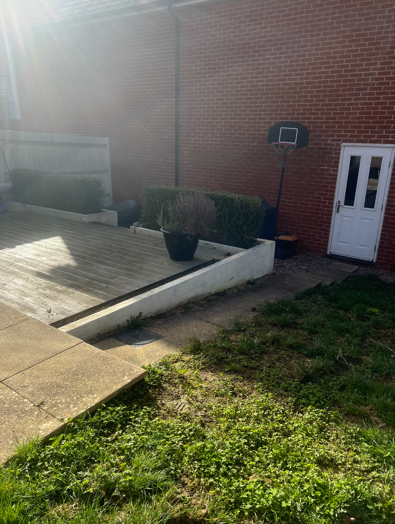 Original garden - tired timber decking and rendered retaining wall beside a patchy lawn