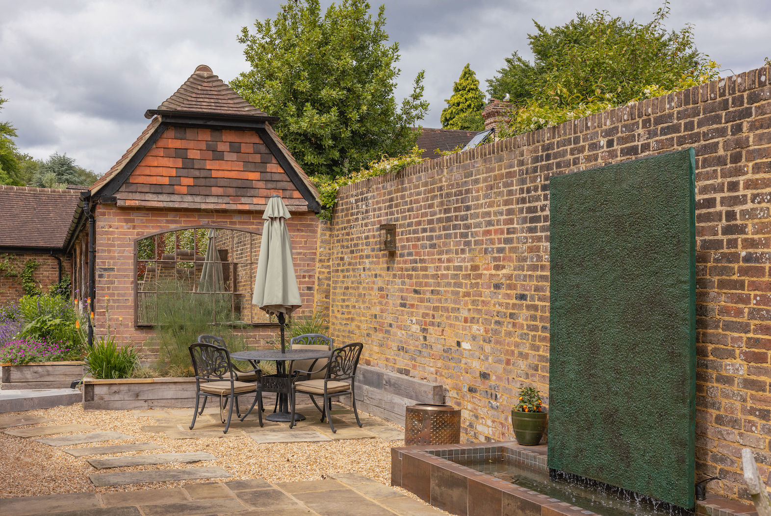 Reclaimed stone courtyard terrace with brick walls and planting