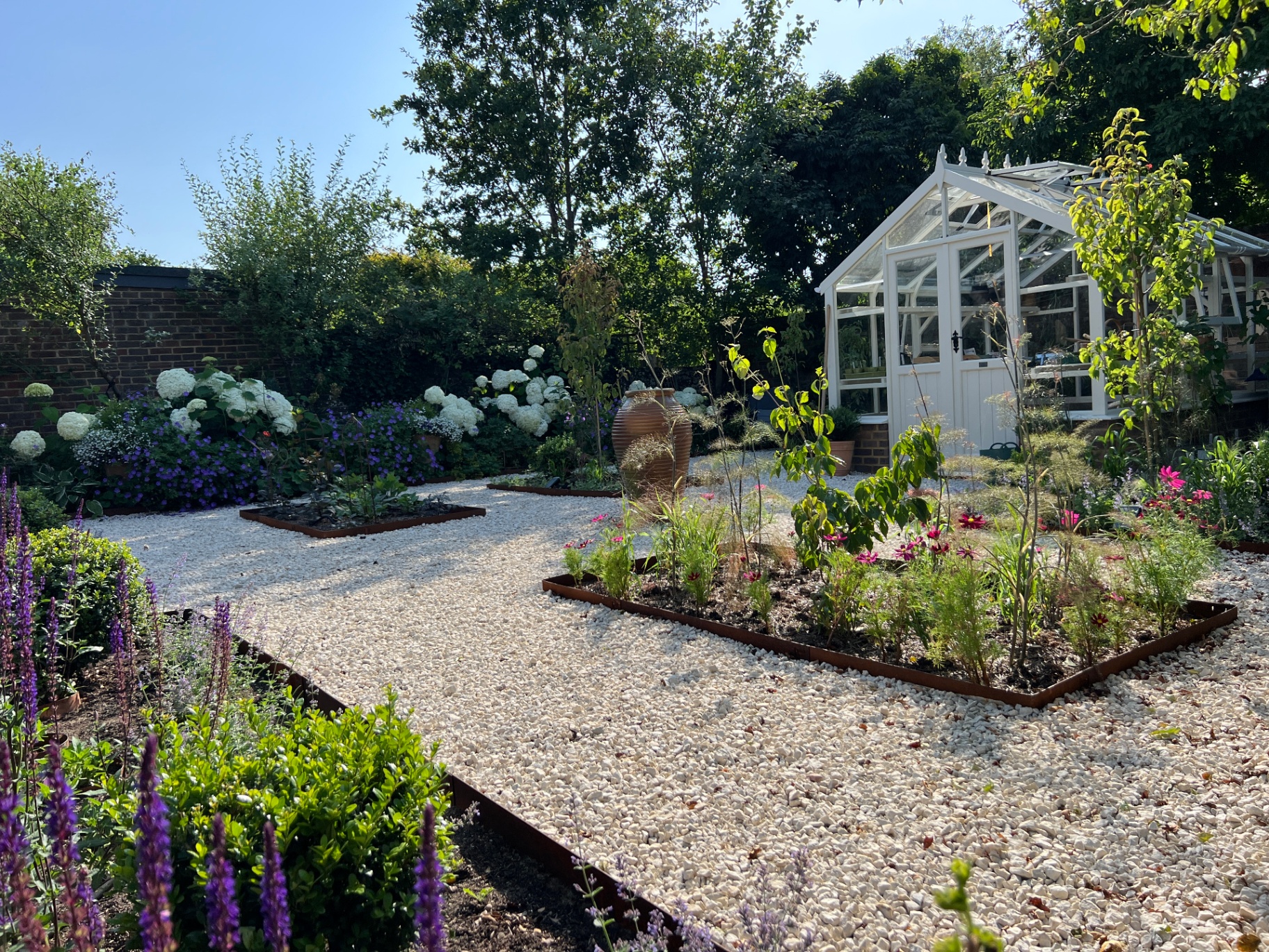 Walled flower garden - gravel pathways, corten-edged beds and a traditional white glasshouse