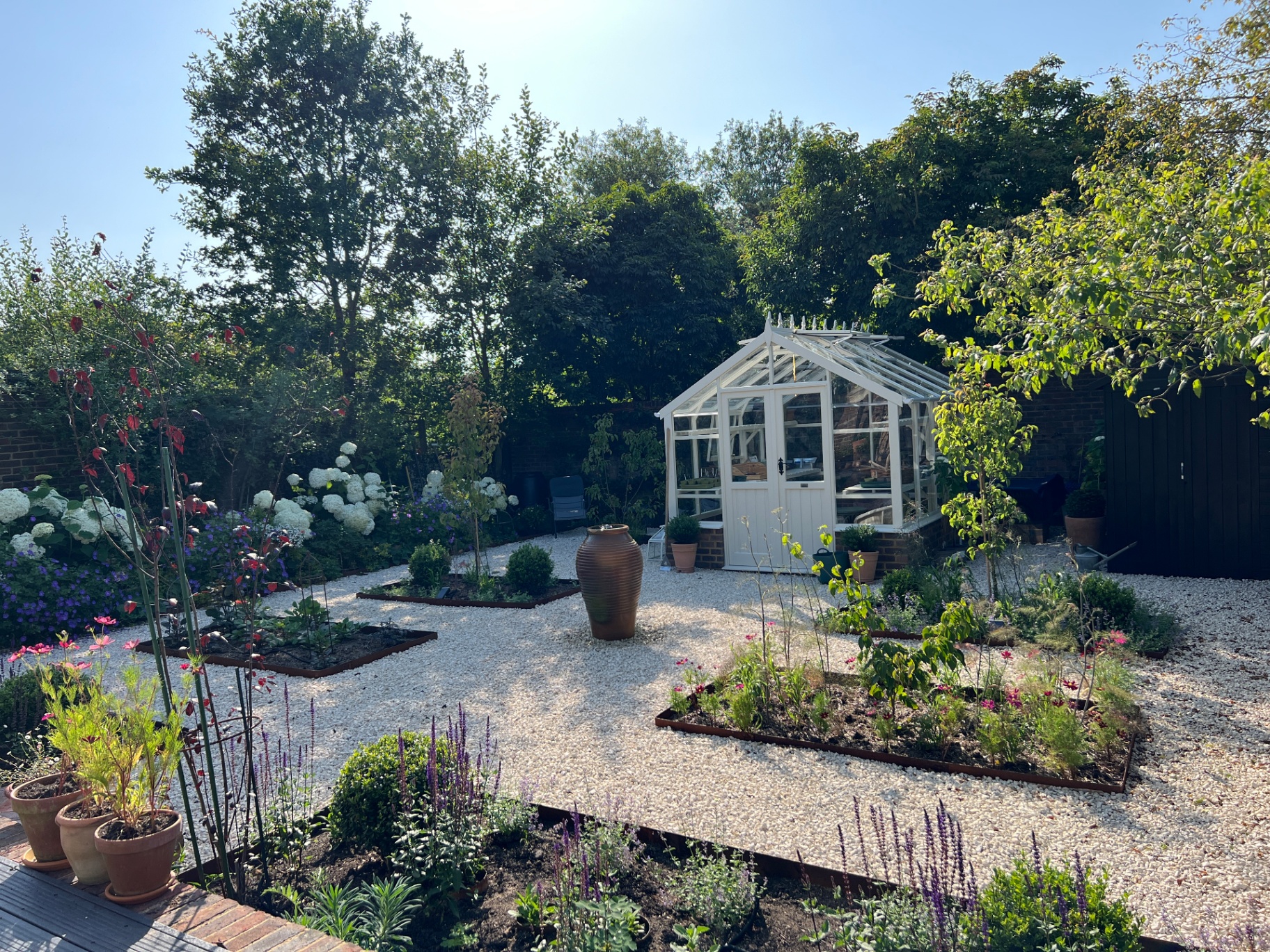 Walled flower garden - central terracotta urn with hydrangeas and cottage-style planting