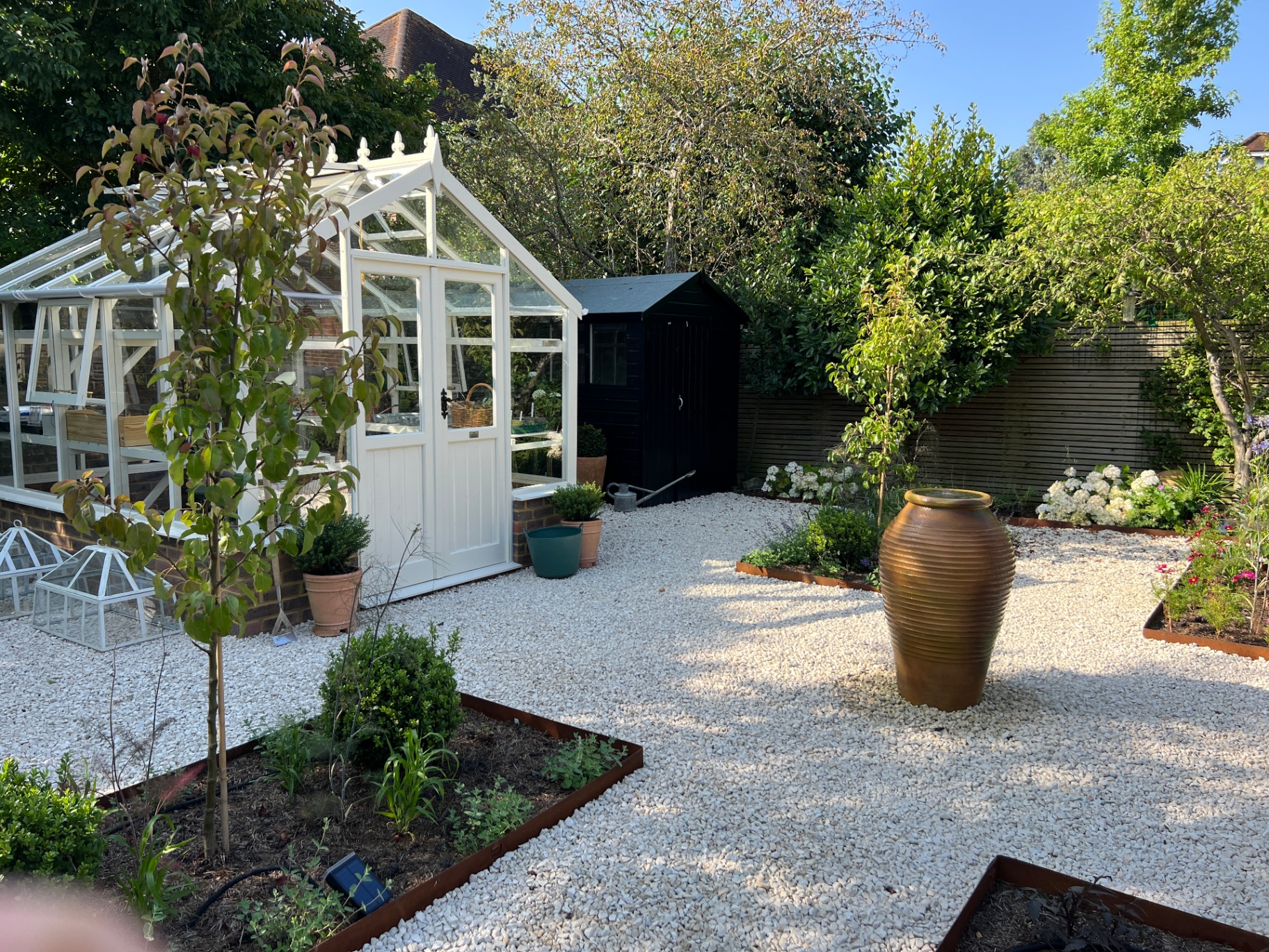 Walled flower garden - side view of the glasshouse, black shed and gravel paths